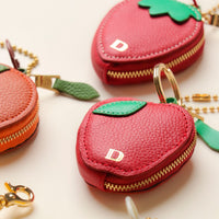 Close-up of leather fruit keychains – strawberry and orange charms with stitching detail and embossed Danilo’s emblem