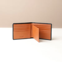 Brown leather wallet with black trim on a beige background