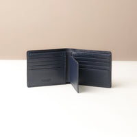Navy leather wallet open on a white surface with a beige background