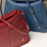 Red Penelope Sr. leather shoulder bag – close-up of premium stitching, dual front pockets, and gold-tone hardware