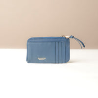 Blue card case wallet with a strap on a beige background