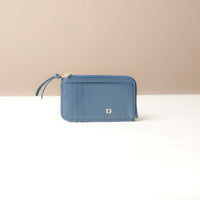 Blue card case wallet with a gold zipper on a beige background