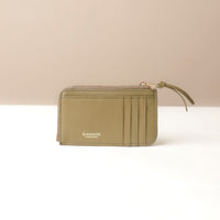 Green card case wallet with a strap on a beige background