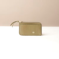 Green card case wallet with a visible brand logo on a beige background