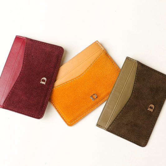 Three leather Danilos card holders in red, yellow, and green on a white background