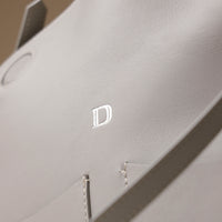 Close-up of D emblem on white Penelope Sr. bag – luxury craftsmanship from Danilo’s