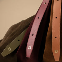 Detail shot of Danilo’s logo on olive and tan suede bags – minimalist branding on premium suede leather