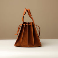 accordion Close-up of tan Suede Papillon Sr. top handles – structured suede and leather craftsmanship