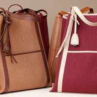 Two handbags, one brown and one burgundy with a white strap, on a light background.
