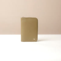 Front view of a green passport case lovable with a Danilos logo on a beige background
