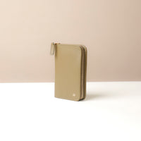 Side view of a green passport case lovable with a Danilos logo on a beige background with zipper