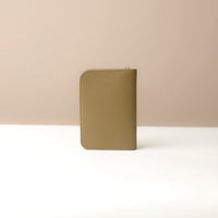 Back view view of a Danilos green passport case lovable on a beige background