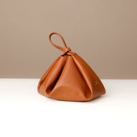 Side view of brown Silueta Bag – minimalist design with triangular fold and wristlet strap