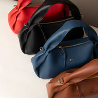 Red, navy, and brown Aurora Soft Bags stacked – artisanal leather shoulder purses with soft structure