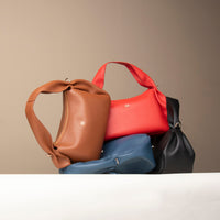 Red, navy, and brown Aurora Soft Bags stacked – artisanal leather shoulder purses with soft structure