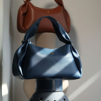 Aurora Soft Bag in navy and brown – sculptural leather shoulder bags stacked on vase de barro