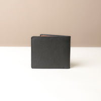 Black leather wallet on a white surface with a beige background