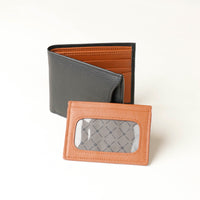Front of a black pebble leather Milano wallet with a orange card case holder over a beige background