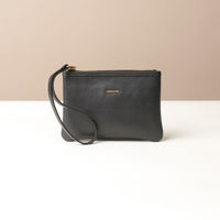 Black leather wristlet pouch with a strap on a beige background