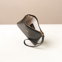 Black wristlet pouch with gold zipper on a white surface