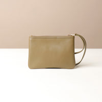Green leather wristlet pouch bag with a strap on a beige background