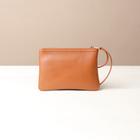 Brown leather wristlet pouch bag with a strap on a beige background