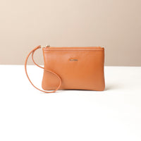 Brown leather wristlet pouch bag with a strap on a beige background