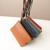 Set of five leather handbags in different colors with zippers on a white surface.