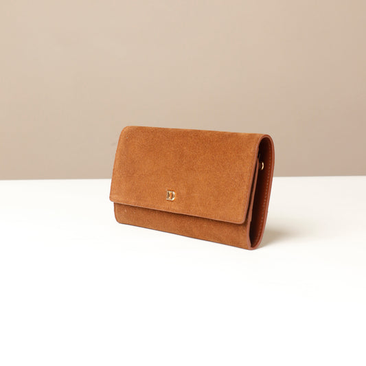 Brown clutch Danilos bag on a white surface with a beige background