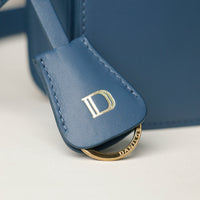 Blue leather product for keys with gold 'D' logo on