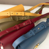 Four crossbody bag with different colored straps on a light background