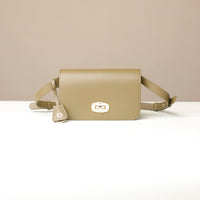 green crossbody bag with a visible brand logo on a beige background