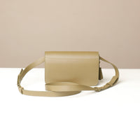 Beige leather crossbody bag on a white surface with a beige background