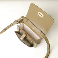 Beige crossbody bag with open flap on a light gray background