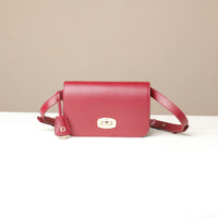 Red crossbody bag with a gold clasp on a beige background