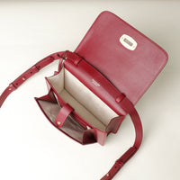 Red crossbody bag with a visible brand logo on a light beige background