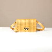 Yellow woven crossbody bag on a white surface with a beige background