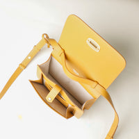 Yellow crossbody bag with a strap on a light background
