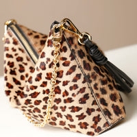 close-up Leopard print crossbody Danilos bag with gold chain and black tassel on a neutral background