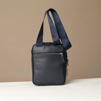 back view of a danilos navy blue crossbody dylan bag with zipper over a beige background