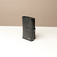 Side view of a black Danilos Pebble executive accessory holder linea on a beige background
