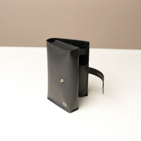 Side view slightly open black Danilos Pebble executive accessory holder linea on a beige background