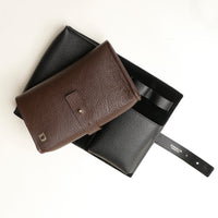 Front view of a black and brown Danilos Pebble executive accessory holder linea on a beige background