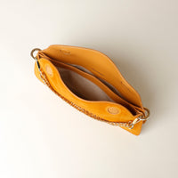 upper view of a small Yellow siede leather danilos handbag with a chain strap on a light beige background