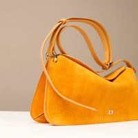 small Yellow suede handbag with a visible danilos  logo on a beige background