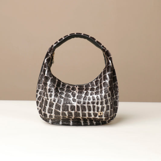 Black and white hair on leather patterned danilos handbag on a beige background