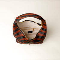 upper view opened hair on leather Striped danilos  handbag with gold zipper on a white background