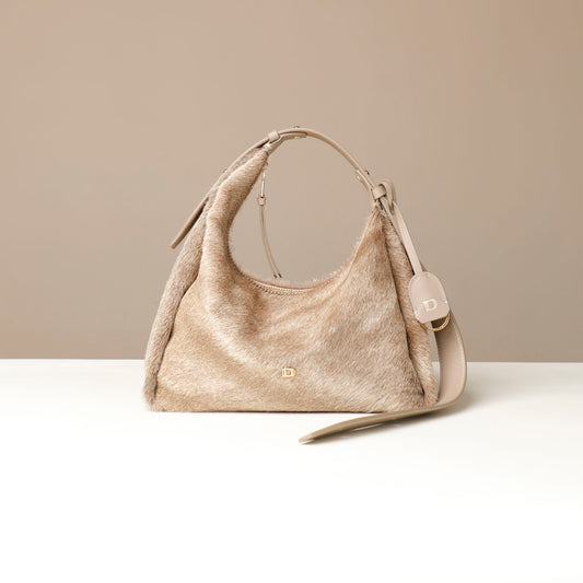 Beige hair on leather Danilos handbag with a strap on a light beige background