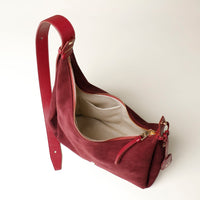 red suede leather danilos handbag with gold zipper on a white background