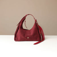 red suede leather handbag with a visible danilos logo on a beige background
